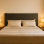 Cabeceira de cama estofada em couro sintético cinza em quarto de casal decorado com iluminação natural