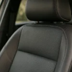 Interior automotivo com detalhe de bancos em courvin perfurado escuro com costura dupla bege — VW T-Cross