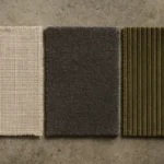 Três amostras de tecido para estofado — linho, chenille e cotelê — sobre superfície de concreto, mostrando textura e diferença de trama